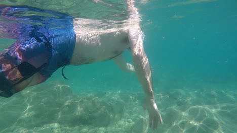 young man at sea with snorkel mask and cliff behind