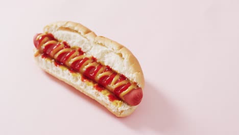 video de un perrito caliente con mostaza y ketchup en una superficie rosa