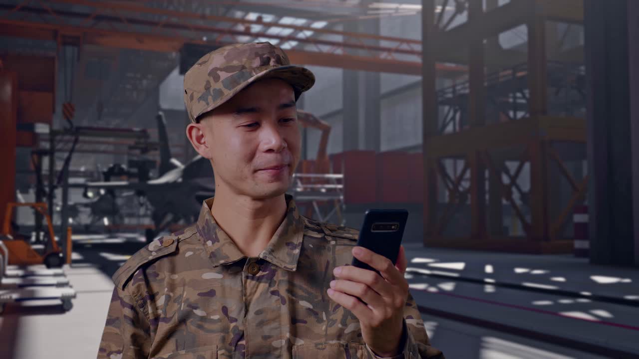Soldato felice che saluta e parla in videochiamata in un hangar