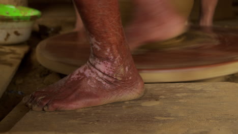 Close-up-of-Asian-woman's-feet-powering-a-foot-operated-turning-table-for-pottery,-a-traditional-technique-for-shaping-and-molding-clay