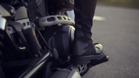 close up shot of a leg in black boots of anonymous biker girl shifting gears