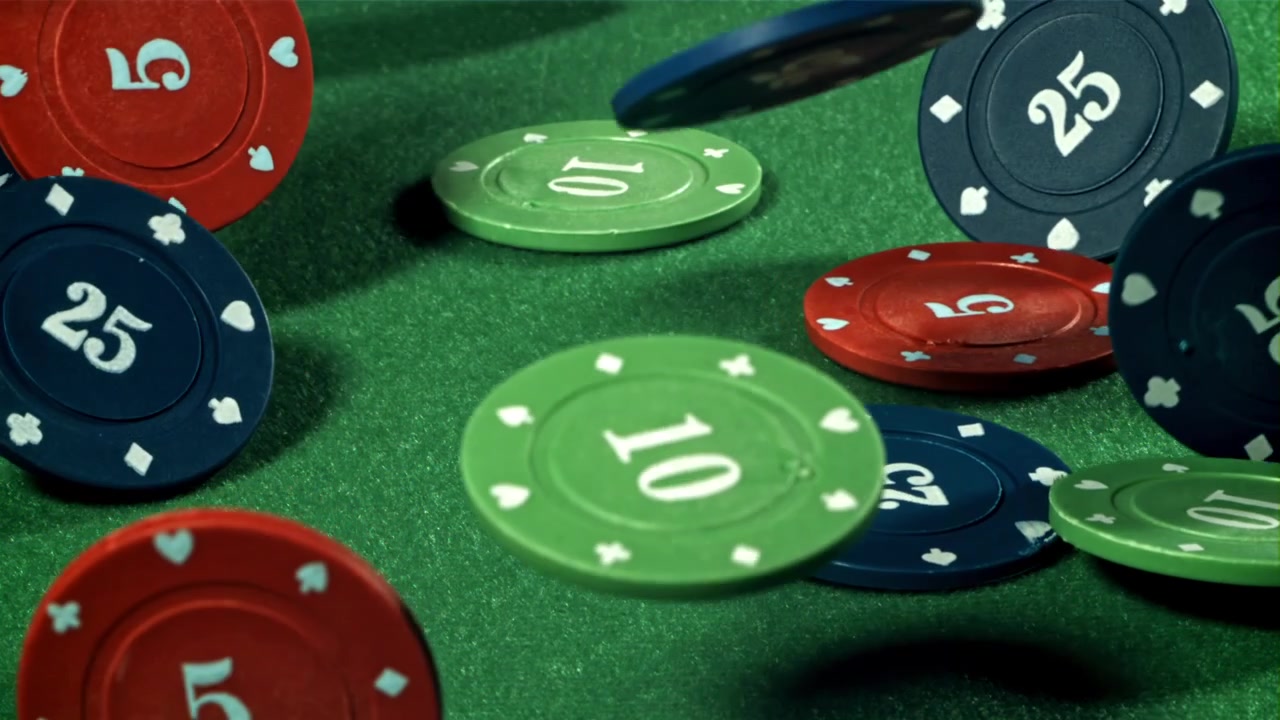 Movimento rallentato di fiches da poker del casinò che cadono su un tavolo di feltro verde