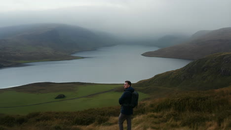 man overlooks a misty mountain lake