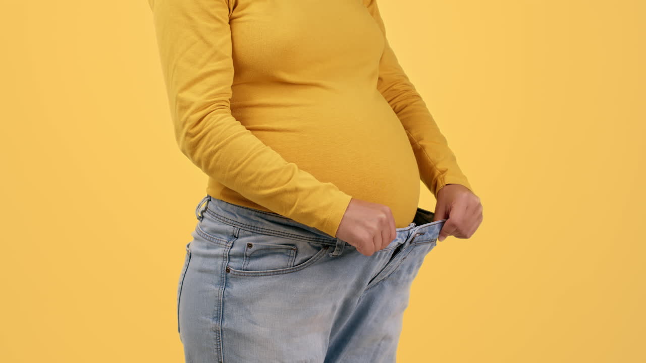Donna incinta che fatica a entrare nei vecchi jeans
