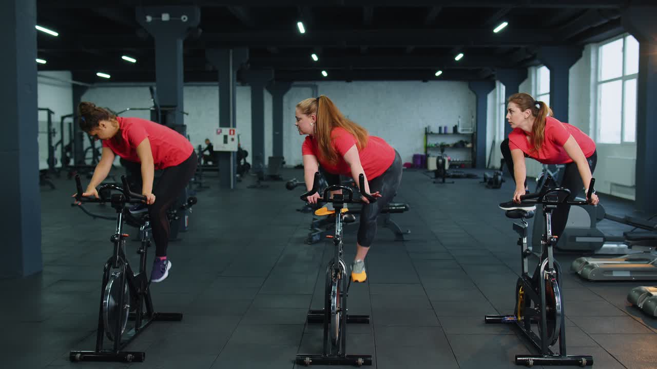 체육관 에서 자전거 를 타고 에어로빅 라이딩 훈련 을 하는 단체 운동 여자 들