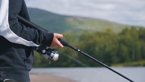 Young-boy-reeling-in-his-fishing-line-on-a-beautiful-lake