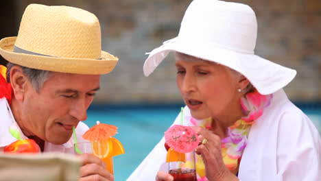 senior couple with garlands drinking colored cocktails