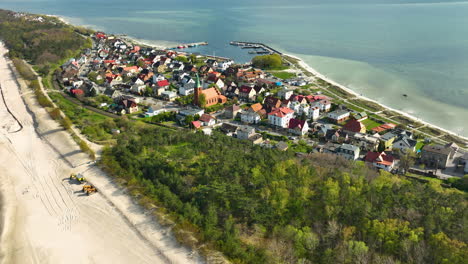 aerial view of kuźnica, a seaside village in pomorskie, poland, with distinctive coastal architecture, nestled between a sandy beach and the blue waters of the baltic sea