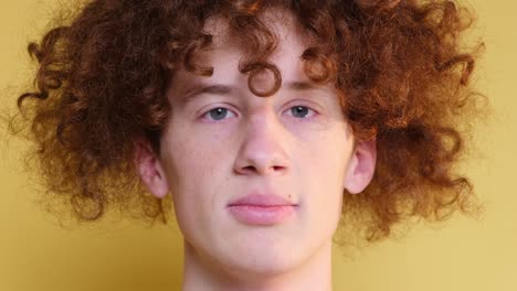 closeup of the face of a curly redhaired boy a student on a light brown background closeup of the face of a curly redhaired boy a student on a light brown background the emotion of peace happiness relaxation meditation a guy with narrowed eyes