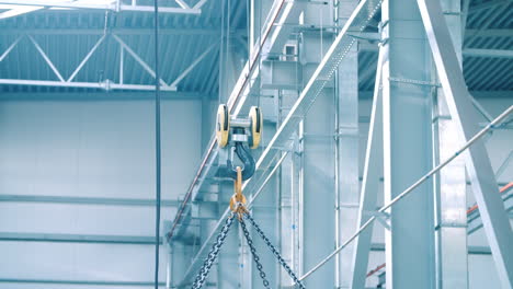 metal hook of crane lifting chains holding heavy load. equipment at plant