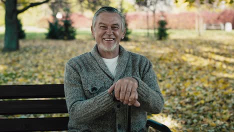 Portrait-of-senior-man-sitting-on-bench-in-park-during-the-autumn.