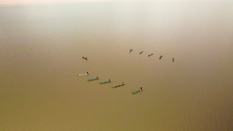 multiple fishermen in bright colorful boars working as a team to catch a shoal of fish