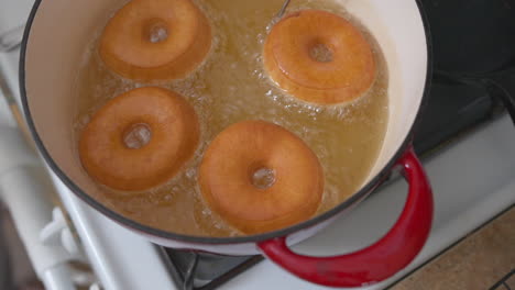 homemade donuts frying in hot oil in a dutch oven on the stove top - slow motion sizzle