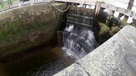 Schleusentore-Für-Geschlossene-Wasserstraßen-In-Zeitlupe,-Kraftvolles-Druckwasser,-Das-Durch-Holzbarrieren-Kaskadiert