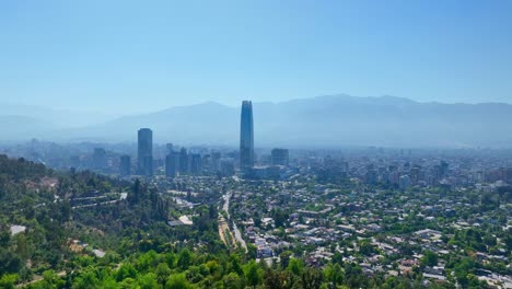 pan drone shot of santiago’s financial district with costanera tower and the andes mountains framing the skyline