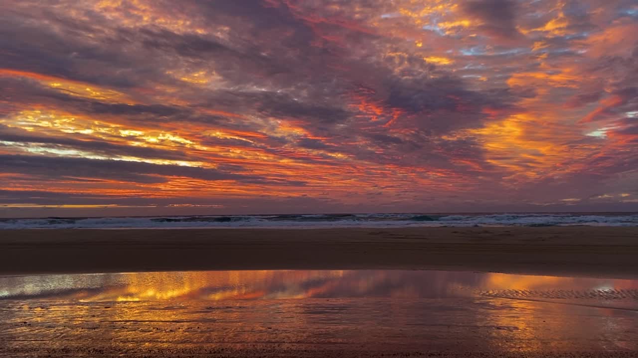 increíble y espectacular amanecer o atardecer en la isla fraser de australia, con una impresionante paleta naranja y dorada como una pintura al óleo, reflejada en el agua acumulada en la playa