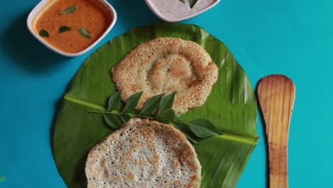 Rotierendes-Südindisches-Essensset-Dosa-Mit-Curry-Und-Chutney-Auf-Blauem-Hintergrund