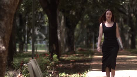 from shade into sunlight woman walks leisurely through the park