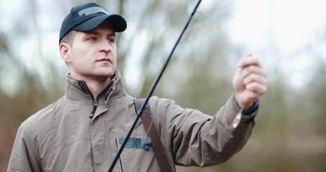 confident man preparing fishing rod at lakeshore 2