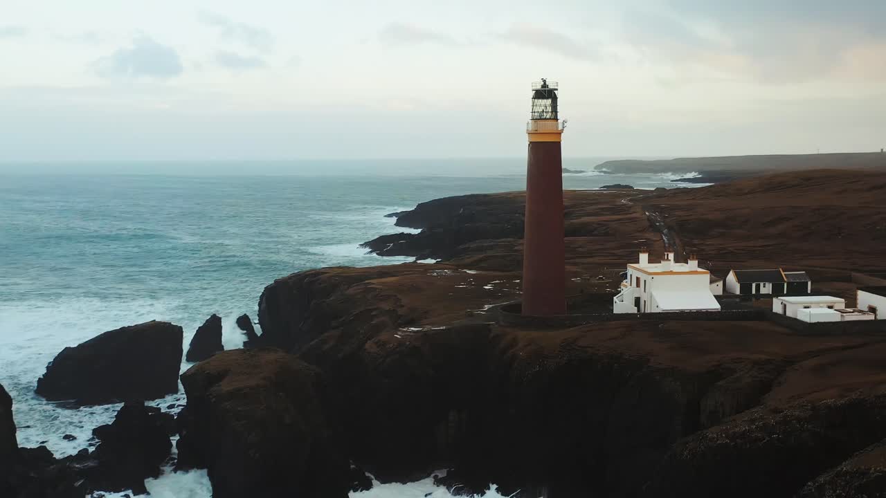 Ripresa di drone con panoramica e inclinazione delle onde che si infrangono attorno al faro di Ness.