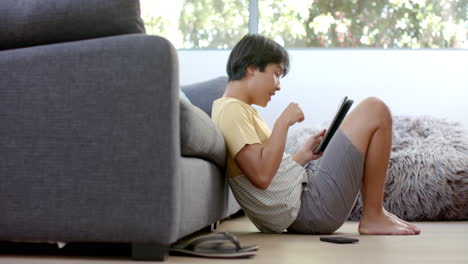 teenage asian boy focused on his tablet at home