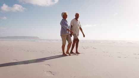 Low-Angle-View-Of-Romantic-Senior-Couple-On-Summer-Vacation-Walking-Along-Beach
