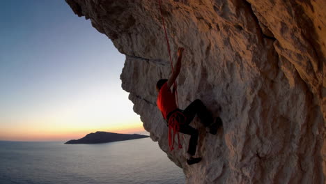 a person rock climbing on a cliff face at sunset over the ocean