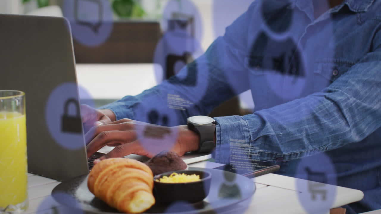 múltiples iconos digitales flotando contra un hombre afroamericano usando una computadora portátil