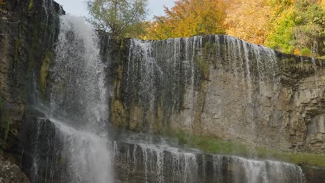 majestic waterfall cascades over rocky cliffs surrounded by autumn trees in a peaceful setting