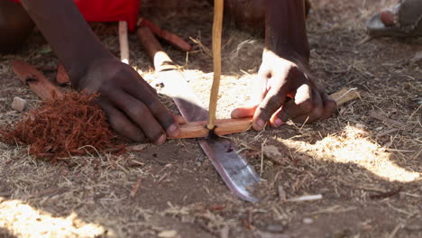 cropped view of a masai men making fire by hand drill in a village in masai mara, kenya