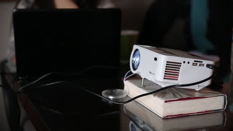 A-projector-sitting-on-a-book,-on-top-of-a-table