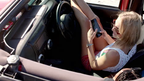 joven mujer caucásica revisa su teléfono en un coche en un viaje por carretera
