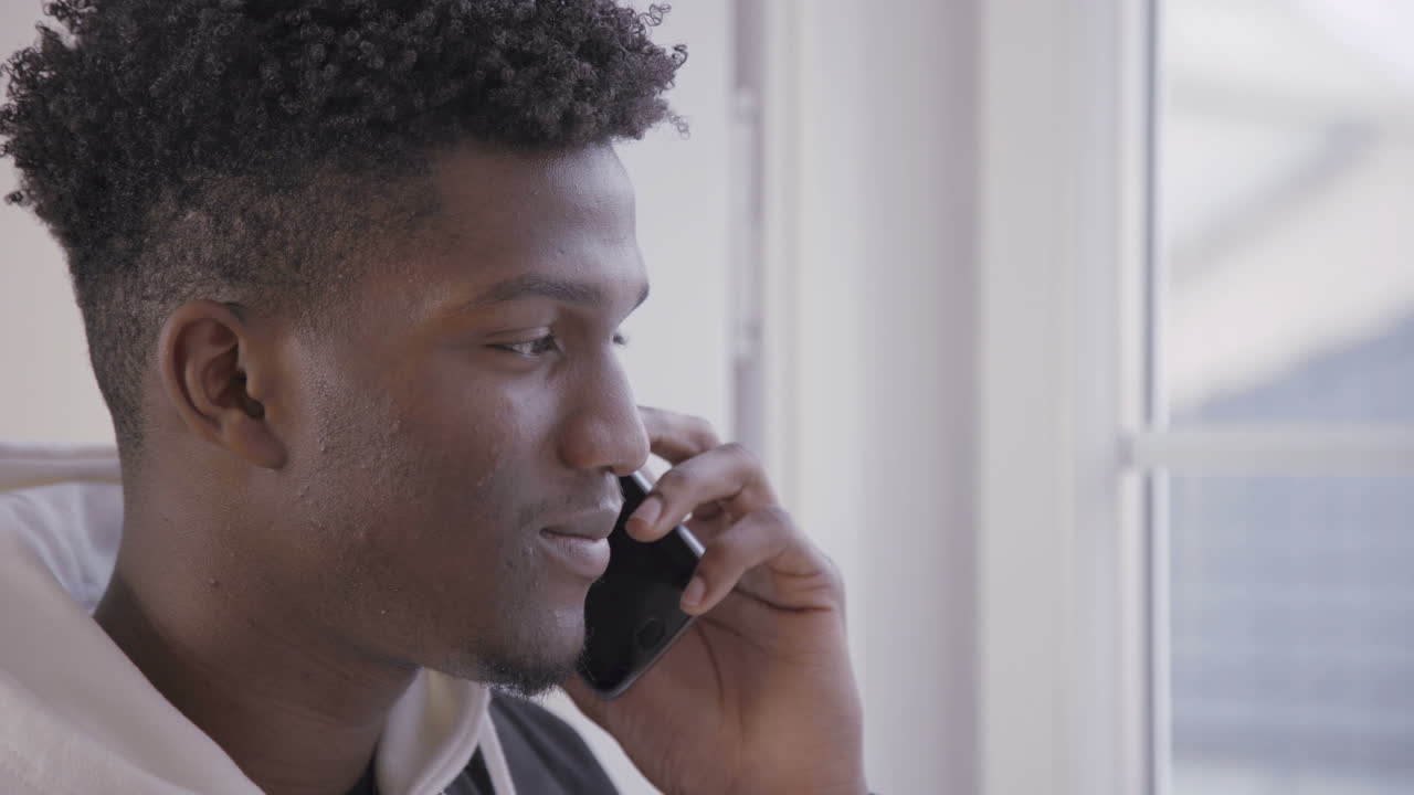 Close-up of smiling young man talking on mobile phone indoors