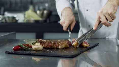 las manos del chef cortando el filete a la parrilla con un cuchillo en la cocina del restaurante