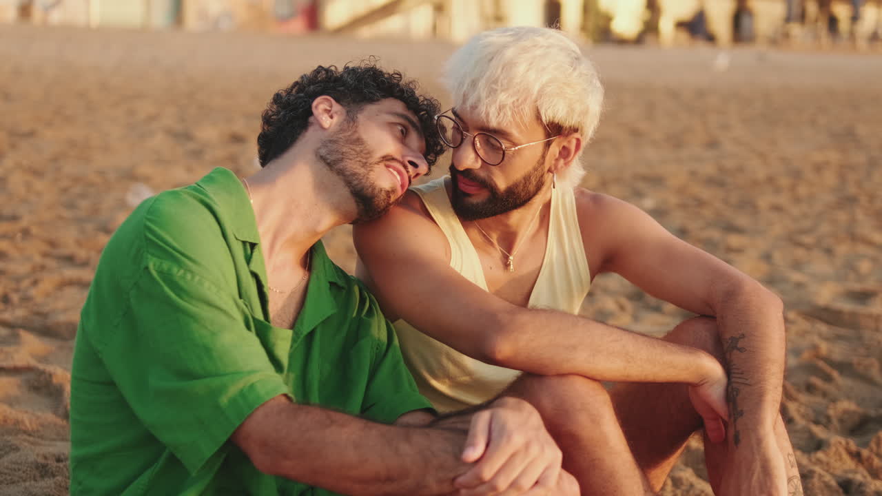 Coppia gay felice che chiacchiera e si scambia effusioni sulla spiaggia