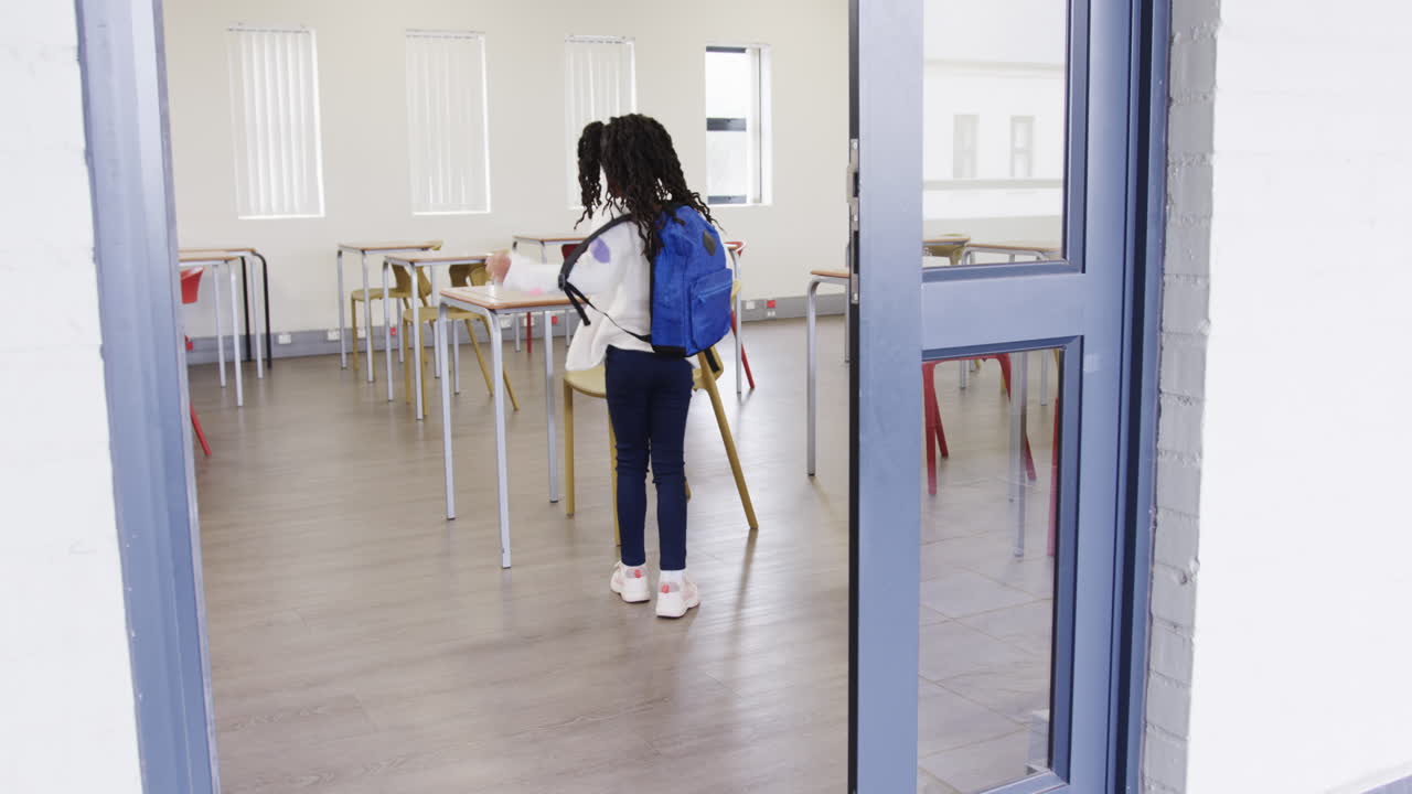 Young girl entering classroom, carrying backpack, preparing for school day