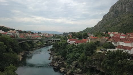 low aerial flies down neretva river to bridge through mostar in bosnia