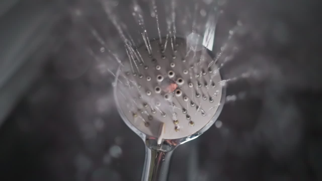 el agua desciende de la cabeza de la ducha de masaje en el baño. equipo doméstico de lavado y relajación del cuerpo en el baño vista inferior. gotas de líquido puro