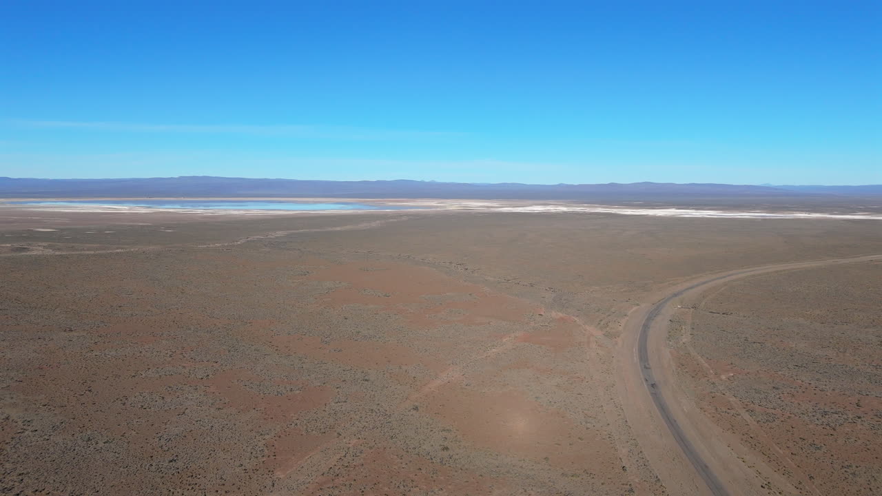 Wide aerial view of a dry desert landscape with a road leading to the horizon near Salinas