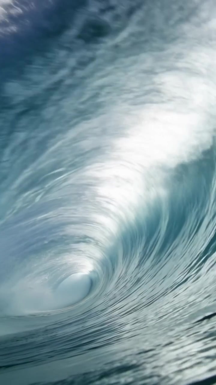 Vertikales Video: Eine aufkommende Dünung drückt eine hohle Welle, die sich mit Gischt über die Kamera im Meer bricht.