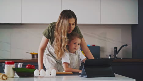 woman with daughter watches cooking recipes with tablet