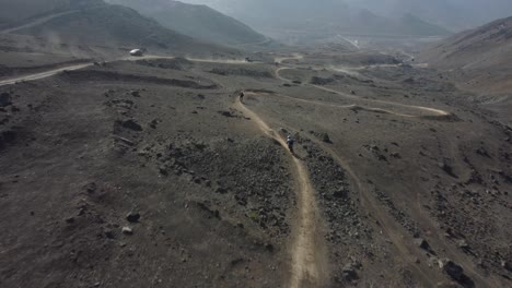 Drohnenaufnahme-Von-Mountainbikern,-Die-Schnell-Einen-Weg-Den-Hang-Hinunter-Fahren