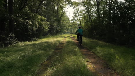 Woman-riding-mountain-bike-down-wooded-dirt-path,-Tracking-Shot,-Slow-Motion