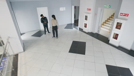 people moving and interacting in an office building hallway