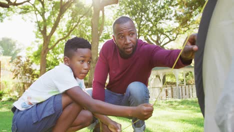 Afroamerikanischer-Vater-Und-Sohn-Bauen-Gemeinsam-Ein-Zelt-Im-Garten-Auf