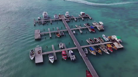 Two-people-walk-down-the-dock-towards-the-boats-sitting-in-the-blue-Caribbean-Sea-in-Aruba