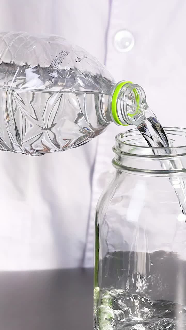 una persona con una bata de laboratorio vierte líquido en un frasco, demostrando un experimento de reacción química