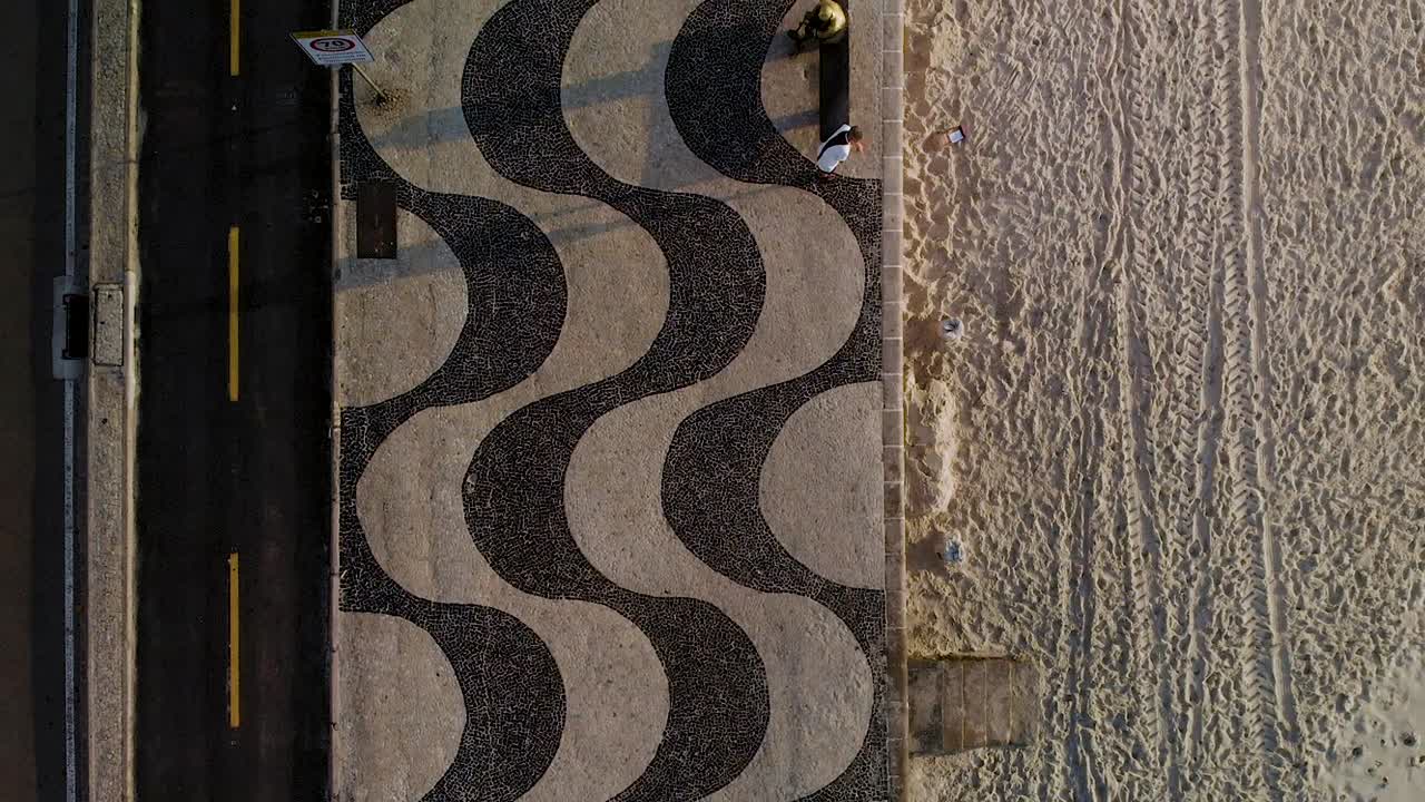 Top down forward moving aerial view of the Copacabana boulevard pavement and beach