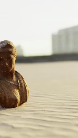ancient sculpture stands alone on sandy beach during golden hour light