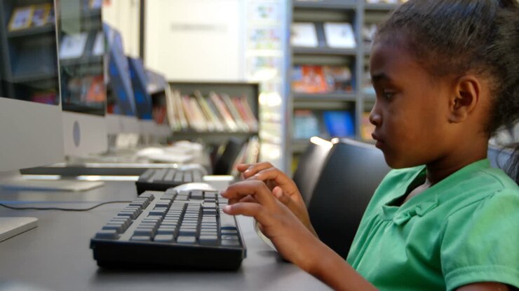 Side view of African American schoolgirl using computer in library at school 4k